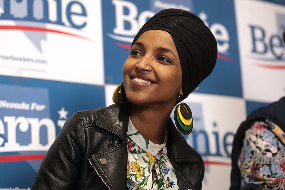 Archive photograph of a woman seated in front of campaign signs.